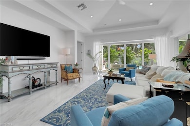 Living room featuring a raised ceiling, plenty of natural light, marble tiled flooring, and recessed lighting