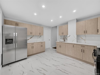 Kitchen with stainless steel fridge, recessed lighting, black range oven, and light brown cabinetry
