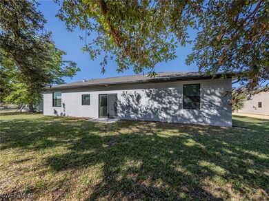 Back of house with a yard and stucco siding