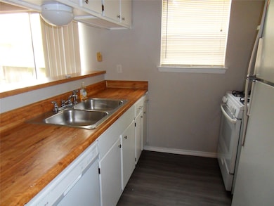 Kitchen with a sink, dark wood-type flooring, whi