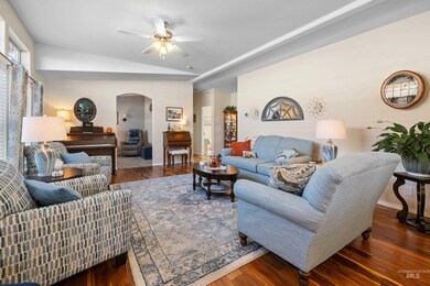 Living area with dark wood-style floors, arched walkways, lofted ceiling, and a ceiling fan