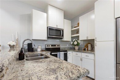 Kitchen featuring stainless steel appliances, open shelves, a sink, white cabinetry, and decorative backsplash