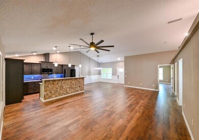 Open plan kitchen, dining, living with volume ceilings.