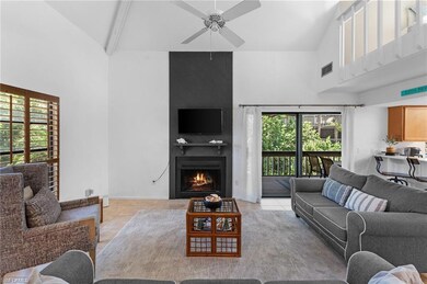 Living room with light tile flooring, ceiling fan, beamed ceiling, a fireplace, and high vaulted ceiling