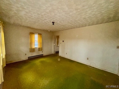 Empty room with a baseboard heating unit and dark carpet