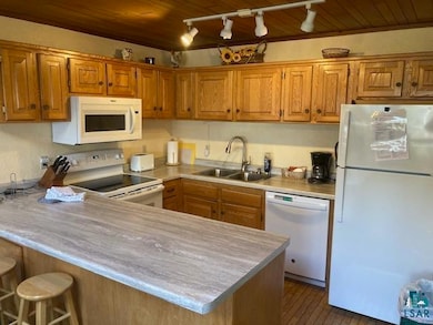 Kitchen with white appliances, a sink, rail lighti