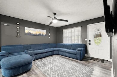Living room featuring a textured ceiling, wood finished floors, and a ceiling fan