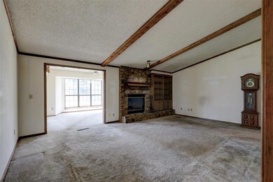 Unfurnished living room with a stone fireplace, and lofted ceiling with beams
