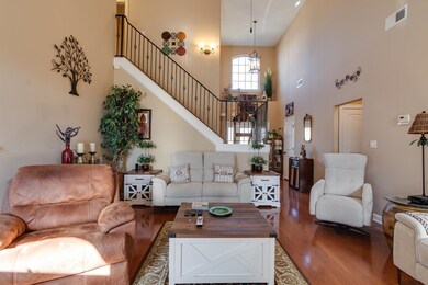 Living area with wood finished floors, a towering ceiling, and stairway