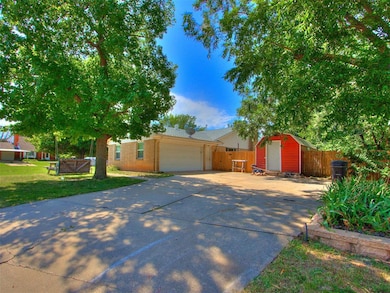 View of front of house with driveway, an attached garage, and a storage shed