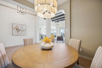 Dining area with arched walkways, wood finished floors, and a chandelier