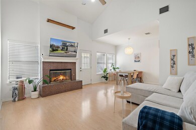 Living room featuring wood finished floors, high vaulted ceiling, a premium fireplace, and a ceiling fan