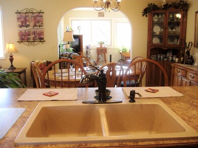 newer granite sink and fixtures overlooking dining/living room and sunroom