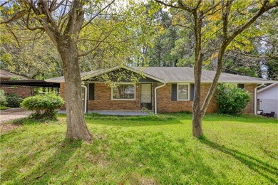 Ranch-style home featuring a front lawn, brick siding, and an attached carport