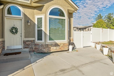 Entrance to property featuring stone siding, a gate, stucco siding, and a patio