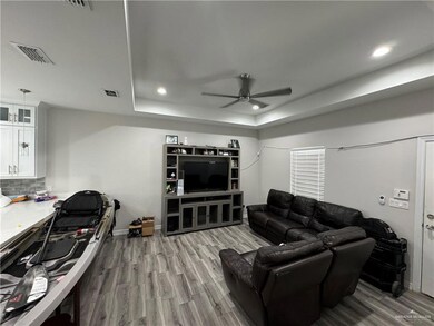 Living room with a ceiling fan, a tray ceiling, wood finished floors, recessed lighting, and baseboards