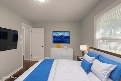 Bedroom featuring dark wood-type flooring and baseboards