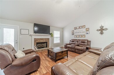 Living area featuring light wood-type flooring, lofted ceiling, and a brick fireplace
