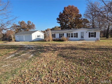 Ranch-style home featuring an outdoor structure, a detached garage, and a front lawn
