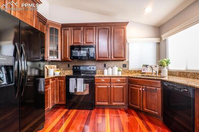 Kitchen featuring glass insert cabinets, a sink, black appliances, light stone counters, and lofted ceiling