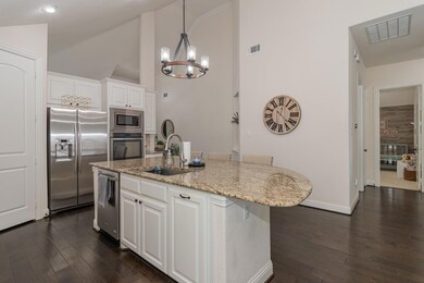 Kitchen with stainless steel appliances, dark wood-type flooring, white cabinetry, and sink