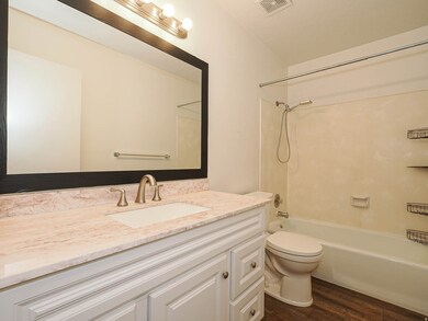 Bathroom featuring dark wood finished floors, bathtub / shower combination, and vanity