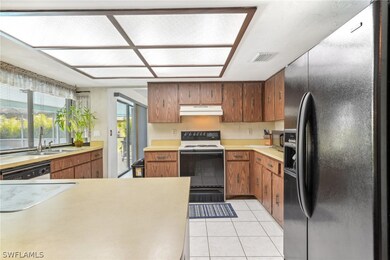 Kitchen with sink, white appliances, and light tile flooring