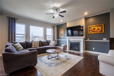 Living room featuring dark wood-type flooring, ceiling fan, and ornamental molding
