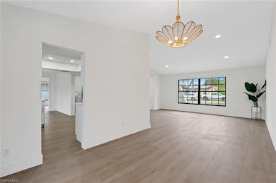 Unfurnished living room featuring baseboards, recessed lighting, wood finished floors, and a chandelier
