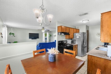 Kitchen with stainless steel fridge, light tile flooring, ceiling fan with notable chandelier, a textured ceiling, and electric range oven