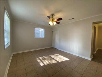 Tiled empty room with ceiling fan and crown moldin