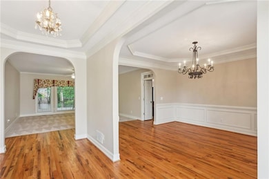 Foyer entrance featuring arched walkways, a chandelier, crown molding, and wood finished floors