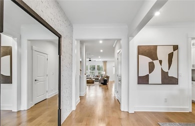 Corridor featuring light wood-type flooring, ornamental molding, and recessed lighting