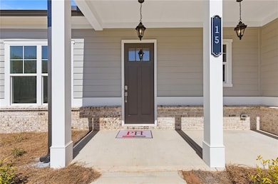 Entrance to property featuring covered porch and brick siding