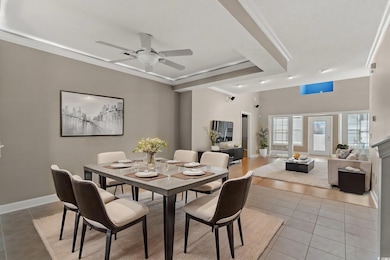 Dining space with light tile patterned floors, a ceiling fan, ornamental molding, and baseboards