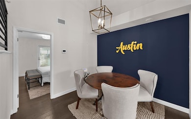 Dining space featuring dark wood-style flooring, a chandelier, and a high ceiling