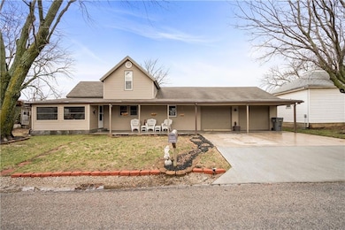 View of front of property with an attached garage, covered porch, a front lawn, and concrete driveway