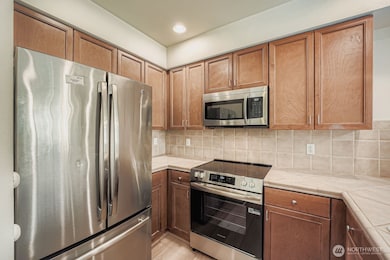 Updated Bellevue condo kitchen with stainless steel fridge, microwave, and electric range.