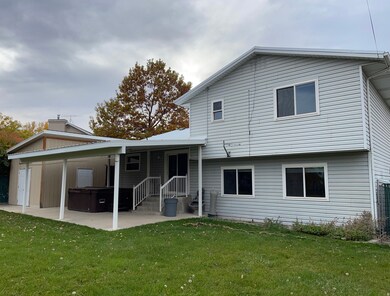 Back of house featuring a hot tub/spa, covered patio, and a large storage shed.