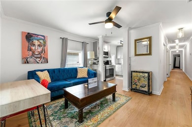 Living room featuring a ceiling fan, light wood fi