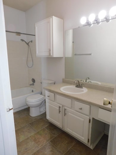 Full bathroom featuring vanity, tub / shower combination, and dark stone finish flooring