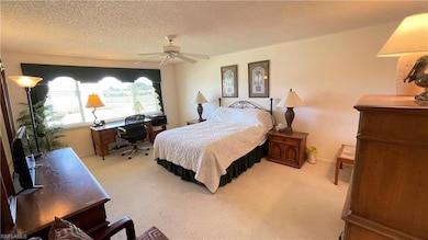 Carpeted bedroom with ceiling fan and a textured c
