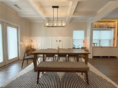 Dining area with coffered ceiling, a chandelier, dark wood finished floors, plenty of natural light, and beamed ceiling