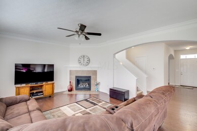 Great Room 18’7 x 14’5 features hardwood flooring, ceiling fan, gas log fireplace with tile surround, tiled hearth and wood mantel, 3 large picture windows with white wood faux blinds and neutral paint