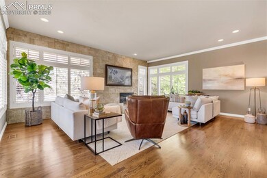 Living room with baseboards, wood finished floors, recessed lighting, a tiled fireplace, and crown molding