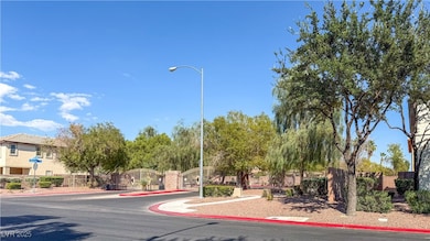 View of asphalt road with curbs, a gated entry, a gate, street lighting, and sidewalks