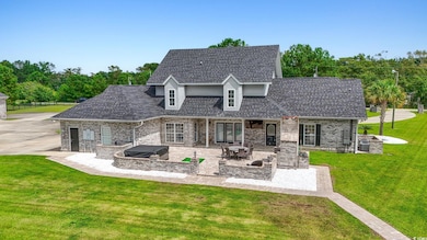 Rear view of property featuring a yard, brick siding, a shingled roof, and a jacuzzi