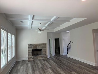Unfurnished living room with a ceiling fan, a fireplace, wood finished floors, beam ceiling, and coffered ceiling