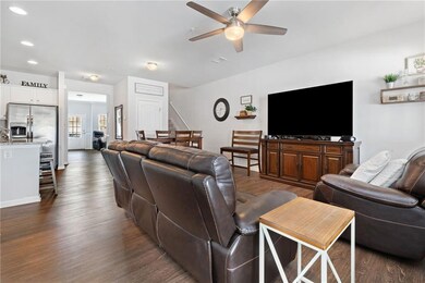 Living area featuring a ceiling fan, dark wood-typ