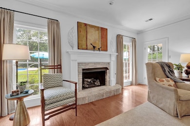 Living room featuring light wood-style flooring, crown molding, and a fireplace